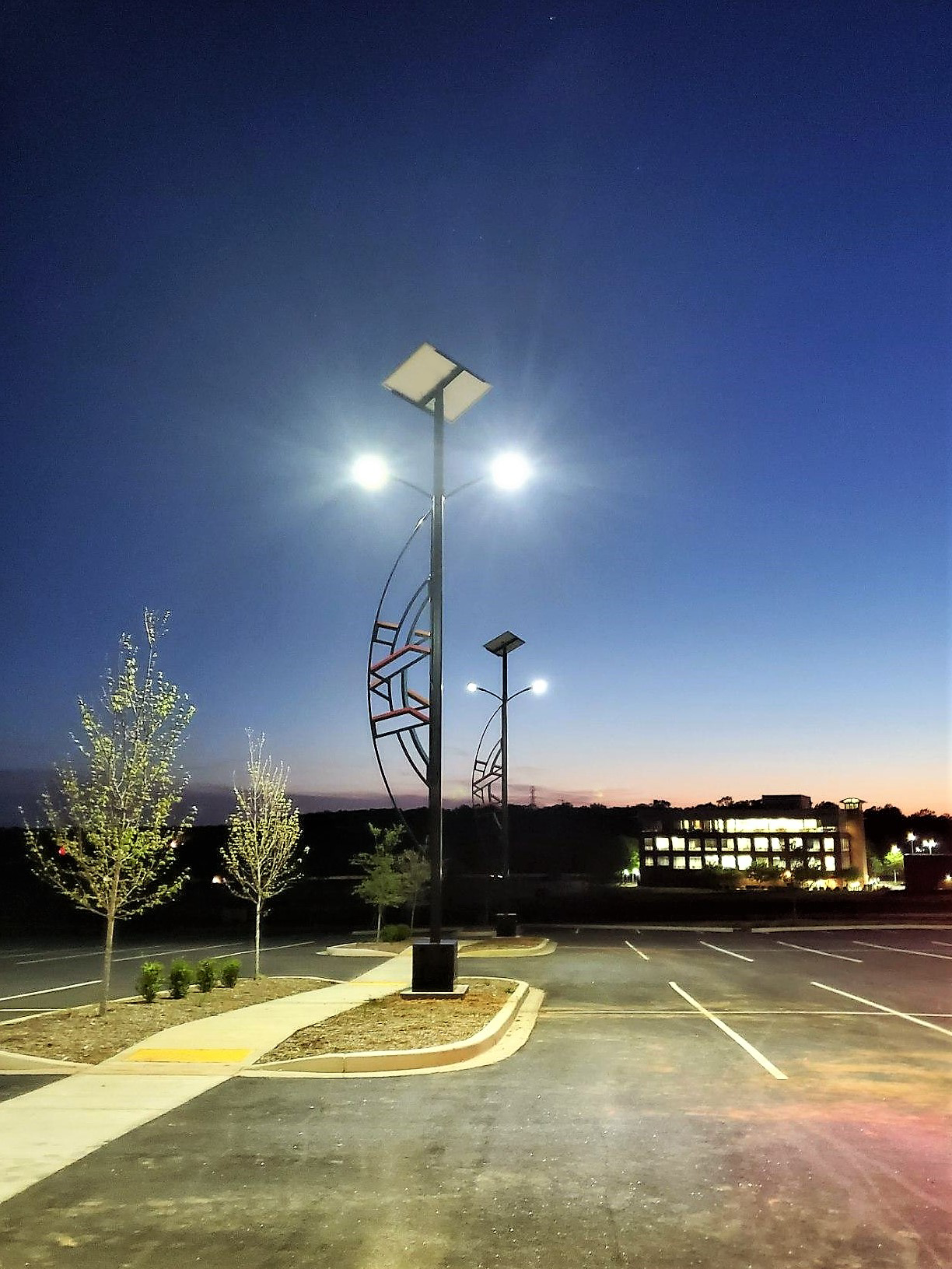 two solar powered parking lot lights with their lights illuminating the parking lot at night