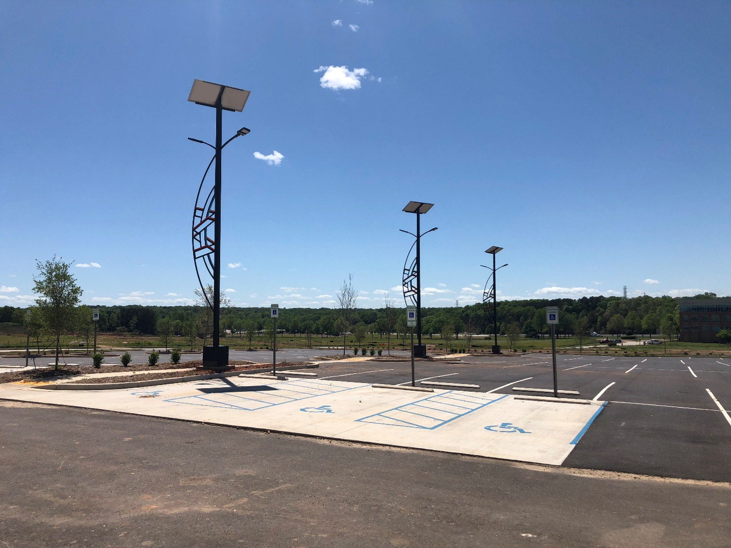 three solar powered parking lot lights in a row during the day